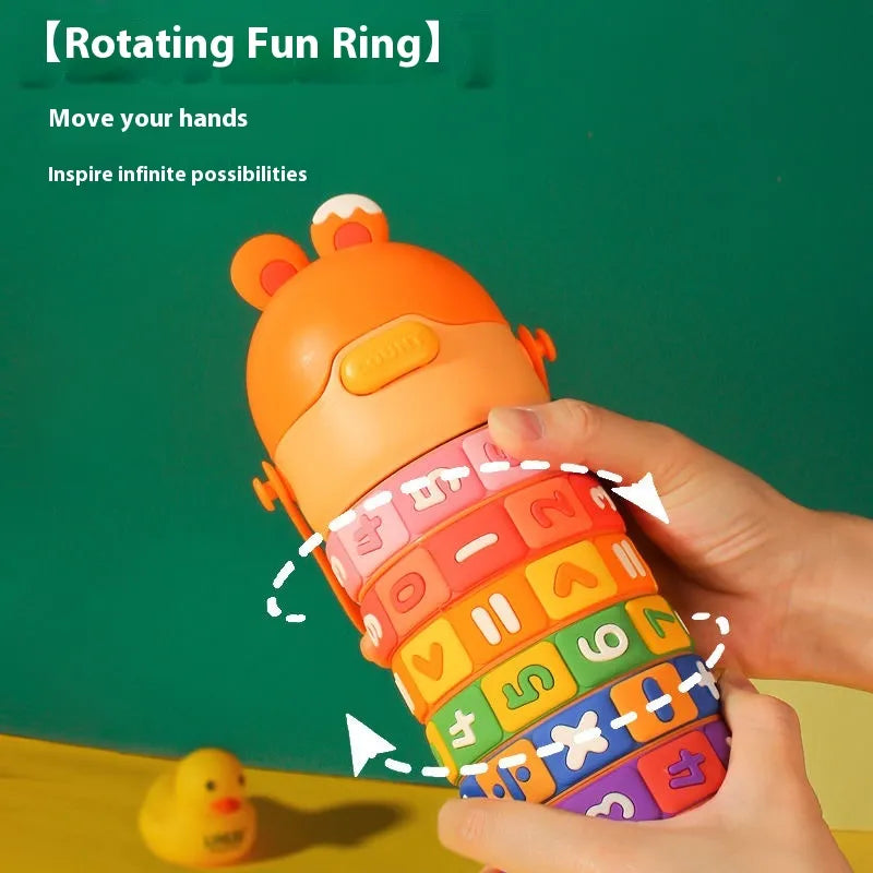 Colorful toy ring with letter and number patterns, held by a hand against a green background.
